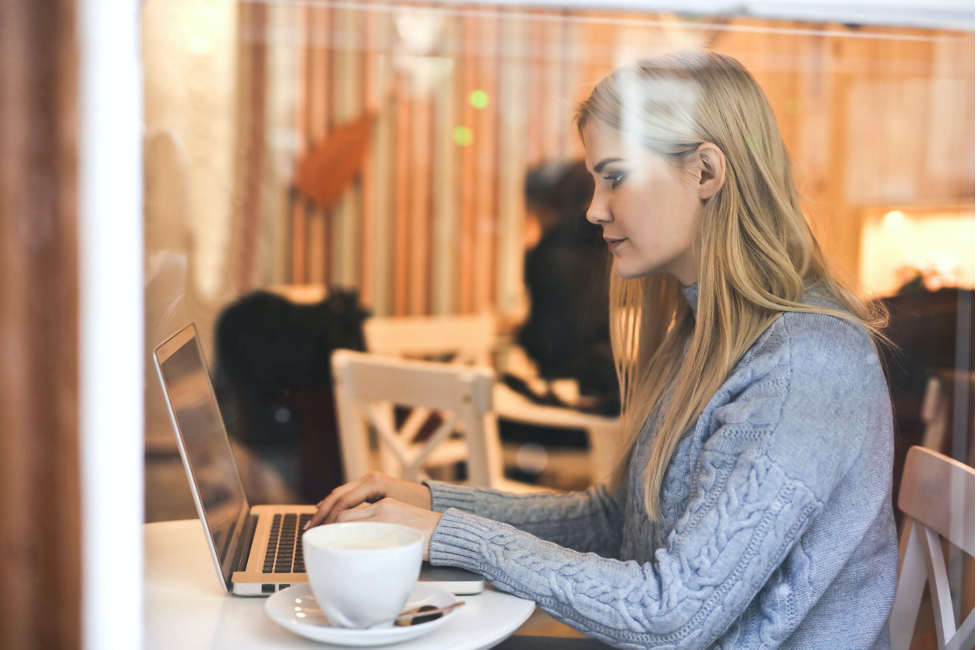 woman sitting in front of a laptop in a coffee shop